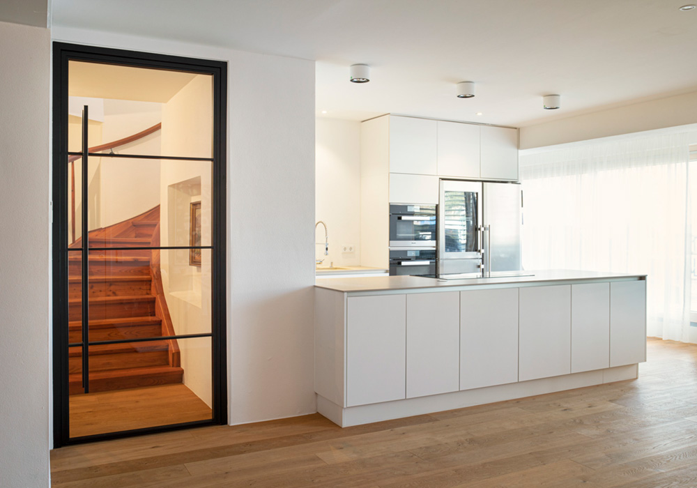 Одностулкові двері в стилі лофт від Hörmann із довгою прямою ручкою між кухнею й коридором.